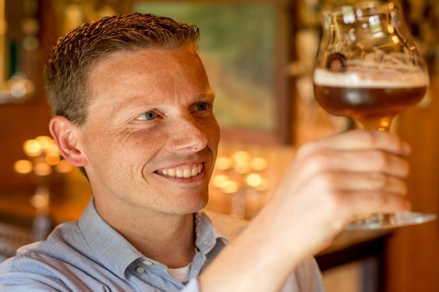 Ein Mann betrachtet frisch gezapftes Bier in einem Glas mit einem Lächeln.