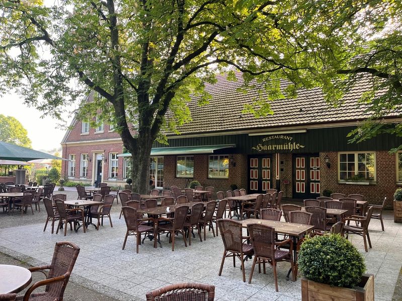 Biertuin met stoelen en tafels voor een huis en bomen